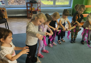 Dzieci w kole przeciągają rolki po sznurku