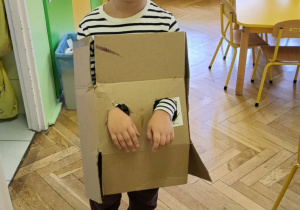 Chłopiec prezentuje swój pojazd wykonany z dużego kartonowego pudła
