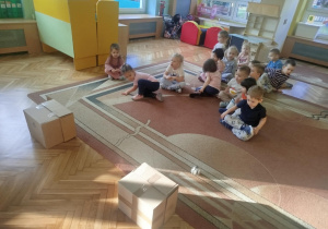 Dzieci w drużynach turlają kule z gazet do tekturowych pudelek