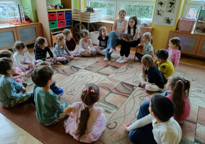 dzieci siedzą w kole, dziewczynki czytają książkę