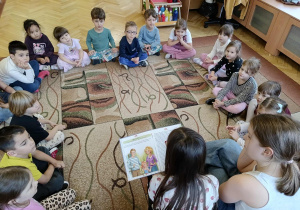 dzieci siedzą w kole, dziewczynki czytają książkę