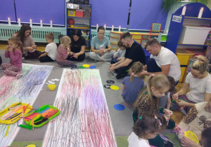 Dzieci wraz z rodzicami wykonują pająki z papierowych talerzyków i drucików kreatywnych.