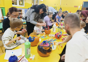 dzieci wraz z rodzicami ozdabiają dynie