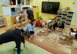 dzieci wraz z rodzicami wykonują asany podczas zabaw ruchowych