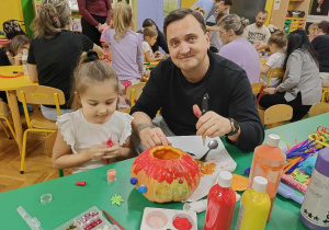 dzieci wraz z rodzicami ozdabiają dynie