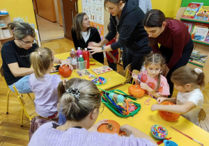 dzieci wraz z rodzicami ozdabiają dynie