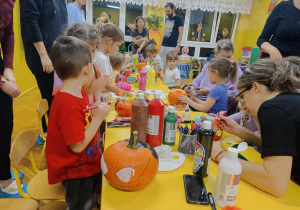 dzieci wraz z rodzicami ozdabiają dynie