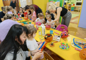 dzieci wraz z rodzicami ozdabiają dynie