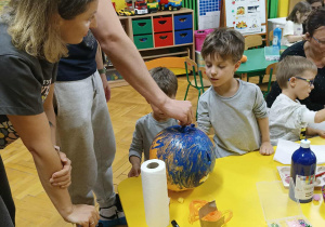 dzieci wraz z rodzicami ozdabiają dynie