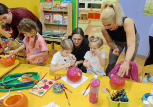 dzieci wraz z rodzicami ozdabiają dynie