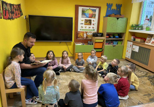 tata Tosi czyta dzieciom książkę „Czerwony kapturek”