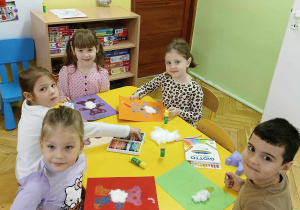 dzieci siedzą przy stoliku, wykonują pracę plastyczną - Miś