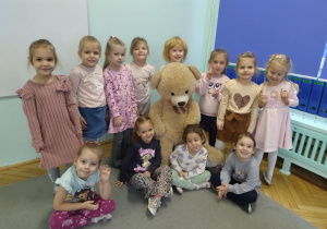Dziewczynki z grupy zielonej ustawione do zdjęcia z misiem.