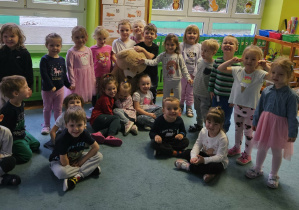 Dzieci pozują do zdjęcia z misiem.