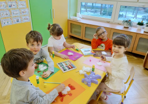 dzieci siedzą przy stoliku, wykonują pracę plastyczną - Miś