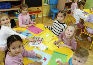 dzieci siedzą przy stoliku, wykonują pracę plastyczną - Miś