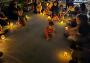 W ciemnościach dzieci i rodzice słuchają muzyki.