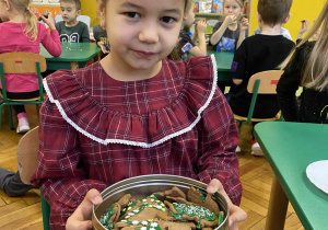 Dziewczynka siedzi na krzesełku trzymając pierniki
