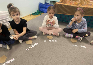 Dzieci siedzą na dywanie naklejają naklejki
