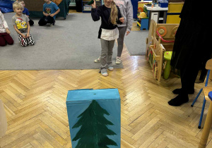 dziewczynka celuje siekierką w tekturowe drzewo,