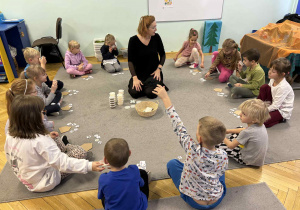 dzieci siedzą w kole i rozpoznają zapachy świąteczne zamknięte w pudełkach
