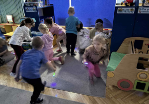 dzieci przy zgaszonym świetle szukają zapalonymi latarkami świecących kamieni