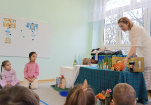 Dzieci słuchająi oglądają inscenizację bajki "Królowa Śniegu" opowiadanej przez prowadzącą warsztaty