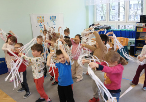 Dzieci tańczą do muzyki z Królowej Śniegu, w ręku trzymając białe wstążki