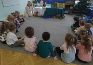 Dzieci słuchająi oglądają inscenizację bajki "Królowa Śniegu" opowiadanej przez prowadzącą warsztaty