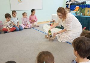 Dzieci słuchająi oglądają inscenizację bajki "Królowa Śniegu" opowiadanej przez prowadzącą warsztaty