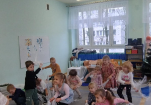 Dzieci tańczą do muzyki z Królowej Śniegu, w ręku trzymając białe wstążki