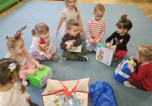 dzieci pozują do zdjęcia z prezentami od Świętego Mikołaja