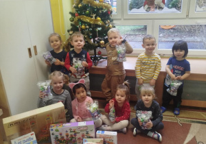 dzieci pozują do zdjęcia z prezentami od Świętego Mikołaja