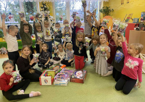 dzieci pozują do zdjęcia z prezentami od Świętego Mikołaja