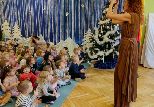 dzieci siedzą na dywanie, słuchają piosenki w języku francuskim