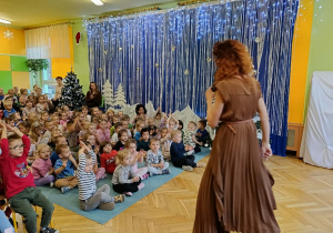 dzieci siedzą na dywanie, słuchają piosenki w języku włoskim