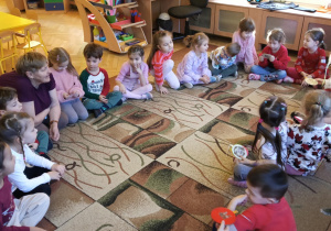 Dzieci siedzą w kole z babcią i mamą Zuzi G., oglądając gotowe bombki