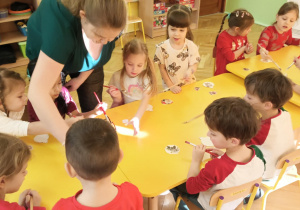 Dzieci smarują drewniane bombki klejem