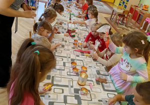 dzieci siedzą przy stole i ozdabiają pierniki