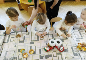 dzieci siedzą przy stole i ozdabiają pierniki