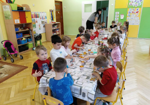 dzieci siedzą przy stole i ozdabiają pierniki