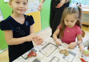 dzieci siedzą przy stole i ozdabiają pierniki