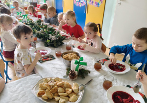 dzieci wspólnie siedzą przy świątecznym stole, spożywają potrawy