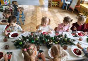dzieci wspólnie siedzą przy świątecznym stole, spożywają potrawy