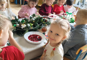 dzieci wspólnie siedzą przy świątecznym stole, spożywają potrawy