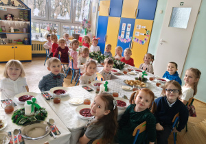 dzieci wspólnie siedzą przy świątecznym stole, spożywają potrawy