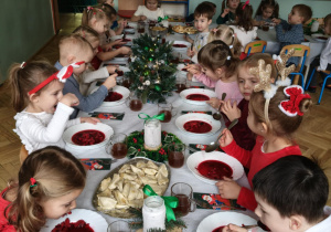 dzieci wspólnie siedzą przy świątecznym stole, spożywają potrawy