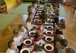 dzieci wspólnie siedzą przy świątecznym stole, spożywają potrawy