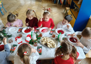 dzieci wspólnie siedzą przy świątecznym stole, spożywają potrawy