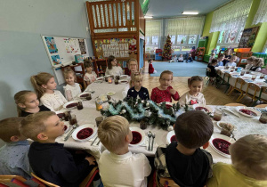 dzieci wspólnie siedzą przy świątecznym stole, spożywają potrawy